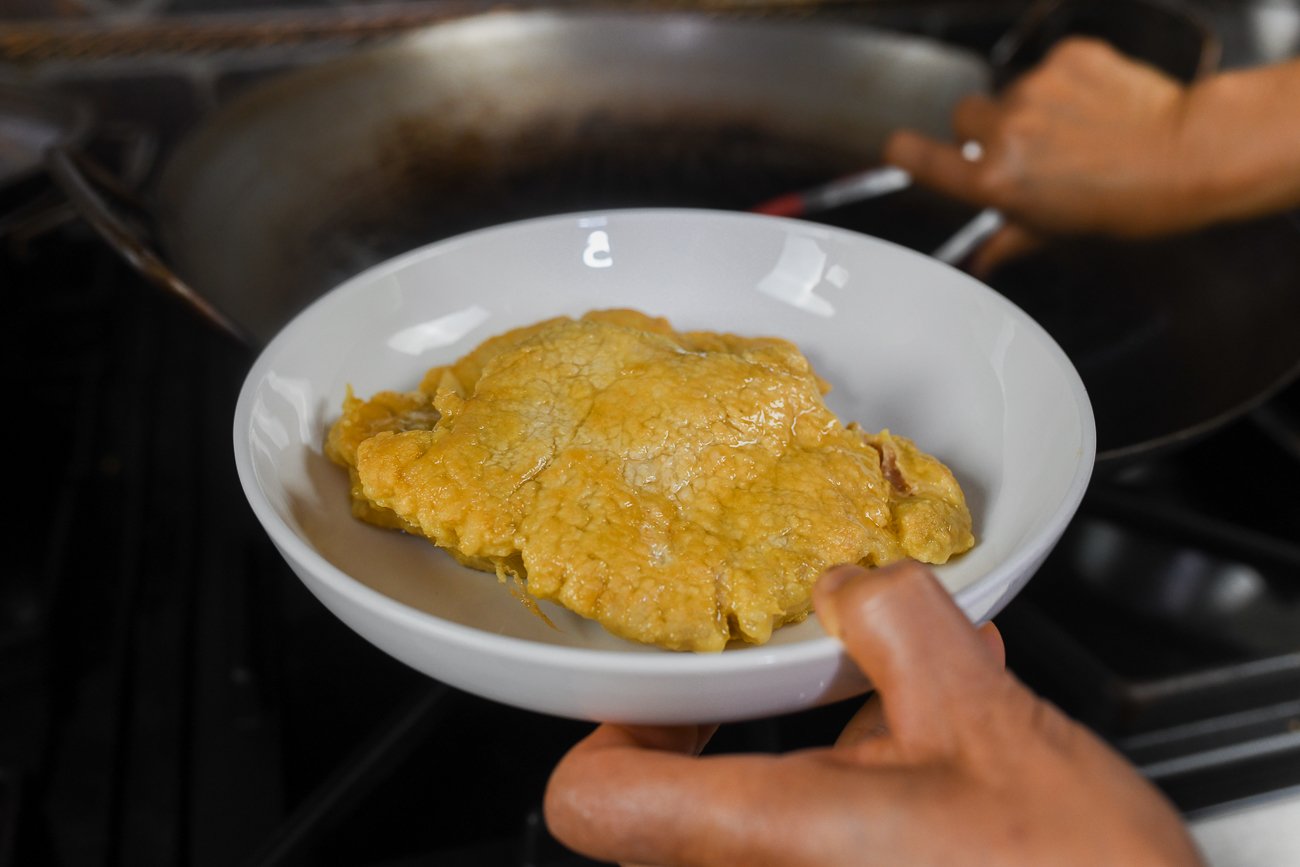 transferring fried pork chops to a dish