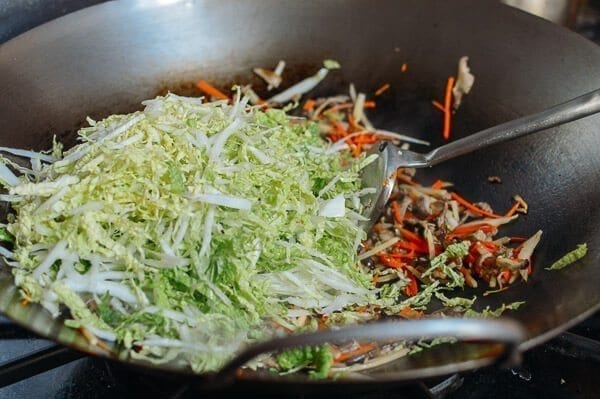 Adding shredded napa cabbage, by thewoksoflife.com